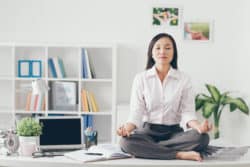 Relaxed employee meditating in her office