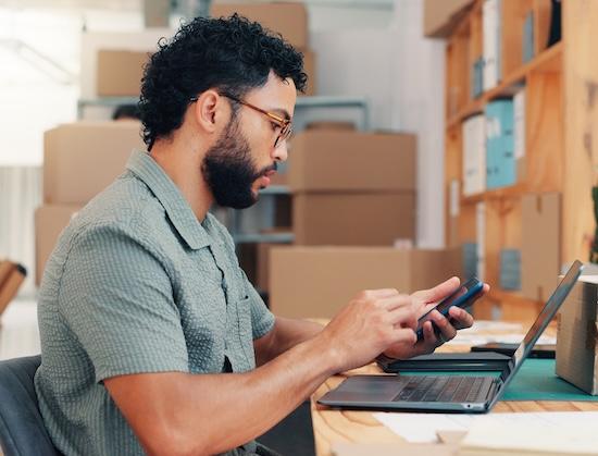 Distributor sales rep checks phone and laptop notifications